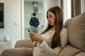 Young woman looking at her mobile while her husband does the housework. concept of gender equality Royalty Free Stock Photo