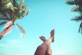 Young women lying on a tropical beach, relax stretching up slender legs tanned.