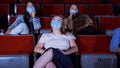 Young women in masks watch movie at cinema. Media. Watching movies in cinemas in context of coronavirus pandemic. People Royalty Free Stock Photo