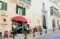 Young women meeting and drinking at outdoor cafe of historical city street with ancient houses