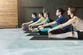 Young women and men in yoga class, doing stretching exercises