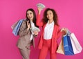 Young women with money and shopping bags on color background Royalty Free Stock Photo