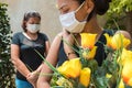 Young woman in mourning, dressed in black with flowers and chewing. Masked people at a funeral