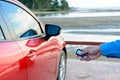 Young women opening his red car door with the control remote key