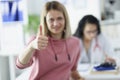 Young woman patient holds thumbs up at doctor appointment
