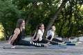 Young women perform stretching for the body. Group fitness lesson outdoors. Morning yoga in park