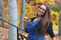Young women portrait outside autumn leaves overalls glasses