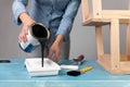 Young women preparing to restore a stepladder for children as a hobby house improvement. Pouring paint into a bucket on a table