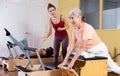 Young pilates instructor helping aged woman exercising on wunda chair Royalty Free Stock Photo