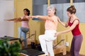 Young pilates instructor helping aged woman exercising on wunda chair Royalty Free Stock Photo