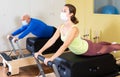 Young woman in protective mask doing pilates exercises on reformer Royalty Free Stock Photo