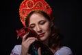 Young women in the red kokoshnik holding cock bird on black background. Russian fairytale.Studio shot Royalty Free Stock Photo