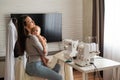 Young woman sews at home and holds a small child. Mom teaches her little son to sew on a sewing machine Royalty Free Stock Photo