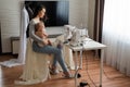 Young woman sews at home and holds a small child. Mom teaches her little son to sew on a sewing machine Royalty Free Stock Photo