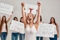 Young caucasian woman with shaved head in white shirt raised her arms, looking enthusiastic. Group of diverse women Royalty Free Stock Photo