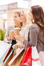Young women with shopping bags and coffee in mall Royalty Free Stock Photo