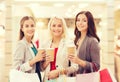 Young women with shopping bags and coffee in mall Royalty Free Stock Photo