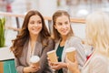 Young women with shopping bags and coffee in mall Royalty Free Stock Photo