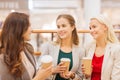 Young women with shopping bags and coffee in mall Royalty Free Stock Photo