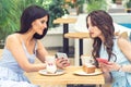 Young woman is showing on cell phone something to girlfriend at cafe. Royalty Free Stock Photo