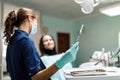 The beautiful young woman is at the dentist. She sits in the dentist`s chair and the dentist carefully examines the patient`s