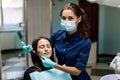 The beautiful young woman is at the dentist. She sits in the dentist`s chair and the dentist carefully examines the patient`s