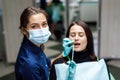 The beautiful young woman is at the dentist. She sits in the dentist`s chair and the dentist carefully examines the patient`s