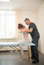 Young woman sitting on the couch and having osteopathic treatment in the clinic - holding her neck with both hands and