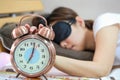 Young women sleepy in bed with blindfold and closed clock. Royalty Free Stock Photo