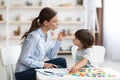 Young woman speech therapist teaching little boy with pronounciation deffects to say sound U during training