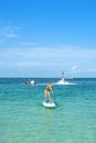 Young woman stand up on board and man posing at new flyboard at Caribbean tropical beach. Standup paddleboarding. Positive human e Royalty Free Stock Photo