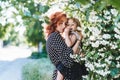 Young woman stands near jasmine with a small daughter