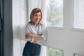 A young woman stands by the panoramic window and smiles at the camera. Royalty Free Stock Photo