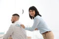 Young woman sticking paper fish to colleague`s back. April fool`s day