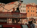 Young women in sunglasses sit on deck of pleasure boat in bay near pier. Advertising Swimming islands. Sea taxi. Glass boat. City