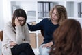 Young woman supporting sad patient at Women`s issues support group