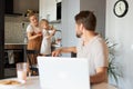 Young woman teach daughter to cook while man is working Royalty Free Stock Photo