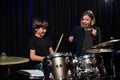 Young woman teaching boy to play drums.