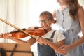 Young woman teaching little girl to play violin indoors Royalty Free Stock Photo