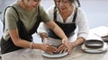 Young woman teaching mature woman making ceramic pot from clay in pottery workshop. Activity, handicraft, hobbies