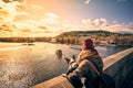 Young women tourist with a puppy dog and a backpack looking at the tourist boat and swans sailing on Vltava river