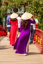 Young women in traditional dress crossing bridge to the Temple of the Jade Mountain, Hanoi, Vietnam