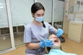 A young woman visits a dental clinic for professional dental treatment. A female dentist leans over a patient. The doctor holds a Royalty Free Stock Photo