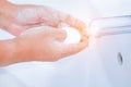 Young women washing hands with soap rubbing fingers and skin under faucet water flows on white basin for pandemic prevention Royalty Free Stock Photo