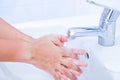 Young women washing hands with soap rubbing fingers and skin under faucet water flows on white basin for pandemic prevention Royalty Free Stock Photo