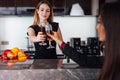 Young women wearing elegant black dress holding a bottle of red wine and a glass standing at kitchen bar looking at her Royalty Free Stock Photo