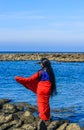 Young women wearing a red saree on the beach. Girl in traditional Indian sari among the rocks and enjoying the freedom. Royalty Free Stock Photo