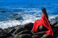 Young women wearing a red saree on the beach. Girl in traditional Indian sari among the rocks and enjoying the freedom. Royalty Free Stock Photo