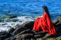 Young women wearing a red saree on the beach. Girl in traditional Indian sari among the rocks and enjoying the freedom. Royalty Free Stock Photo
