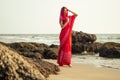 Young women wearing a red saree on the beach goa India.girl in traditional indian sari on the shore of a paradise island